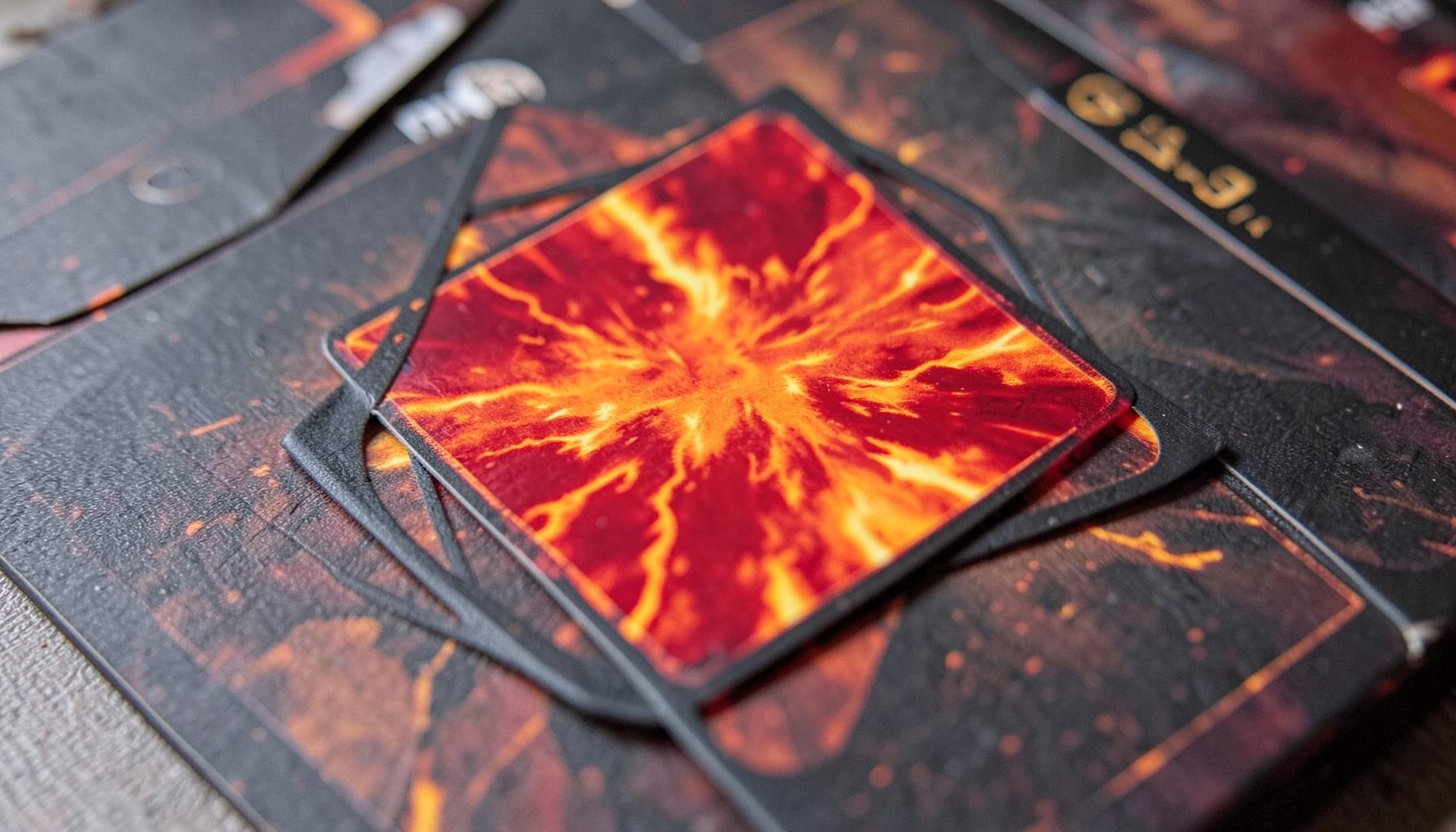 A red burn spell card resting on a playmat, fiery oranges and reds with a dark charcoal border.